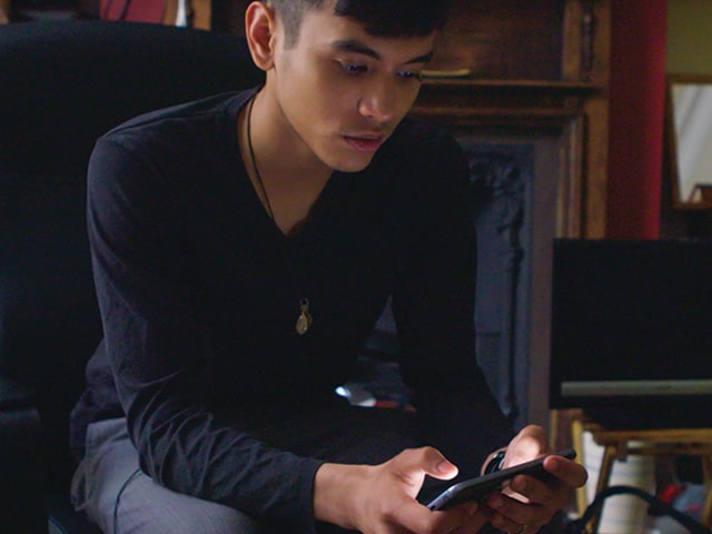 Boy wearing dark shirt plays videogame on smartphone