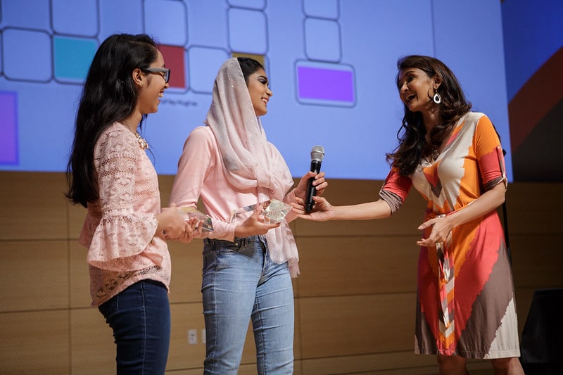 Woman gives award to other woman wearing a hijab on a stage