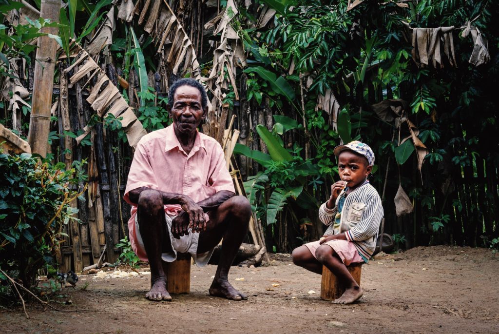 A man and a child sit in nature while looking at the camera