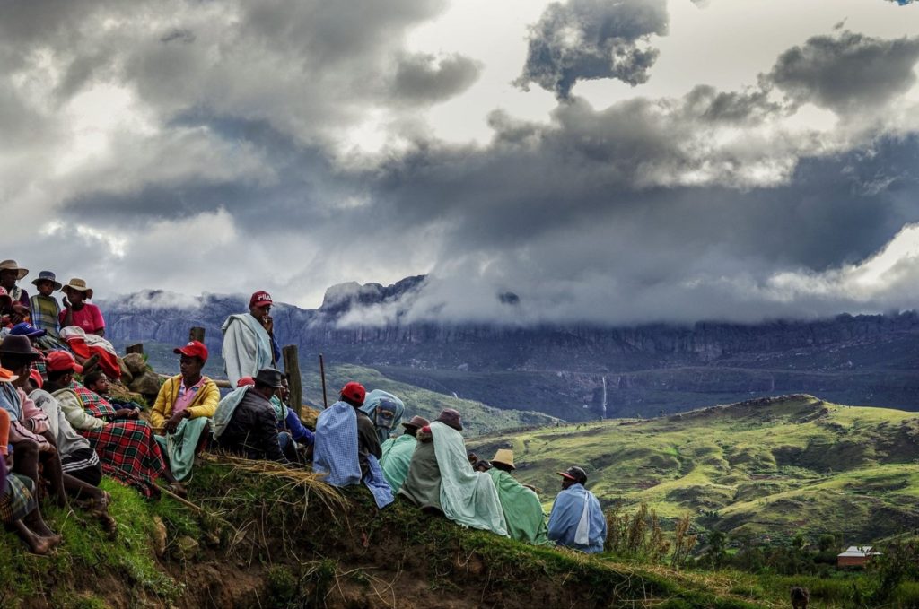 Group of people standing on a hill with cloudy mountains in the background