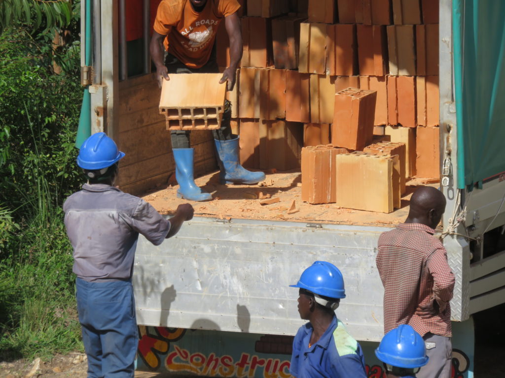Men in construction gear work together unloading bricks from a truck